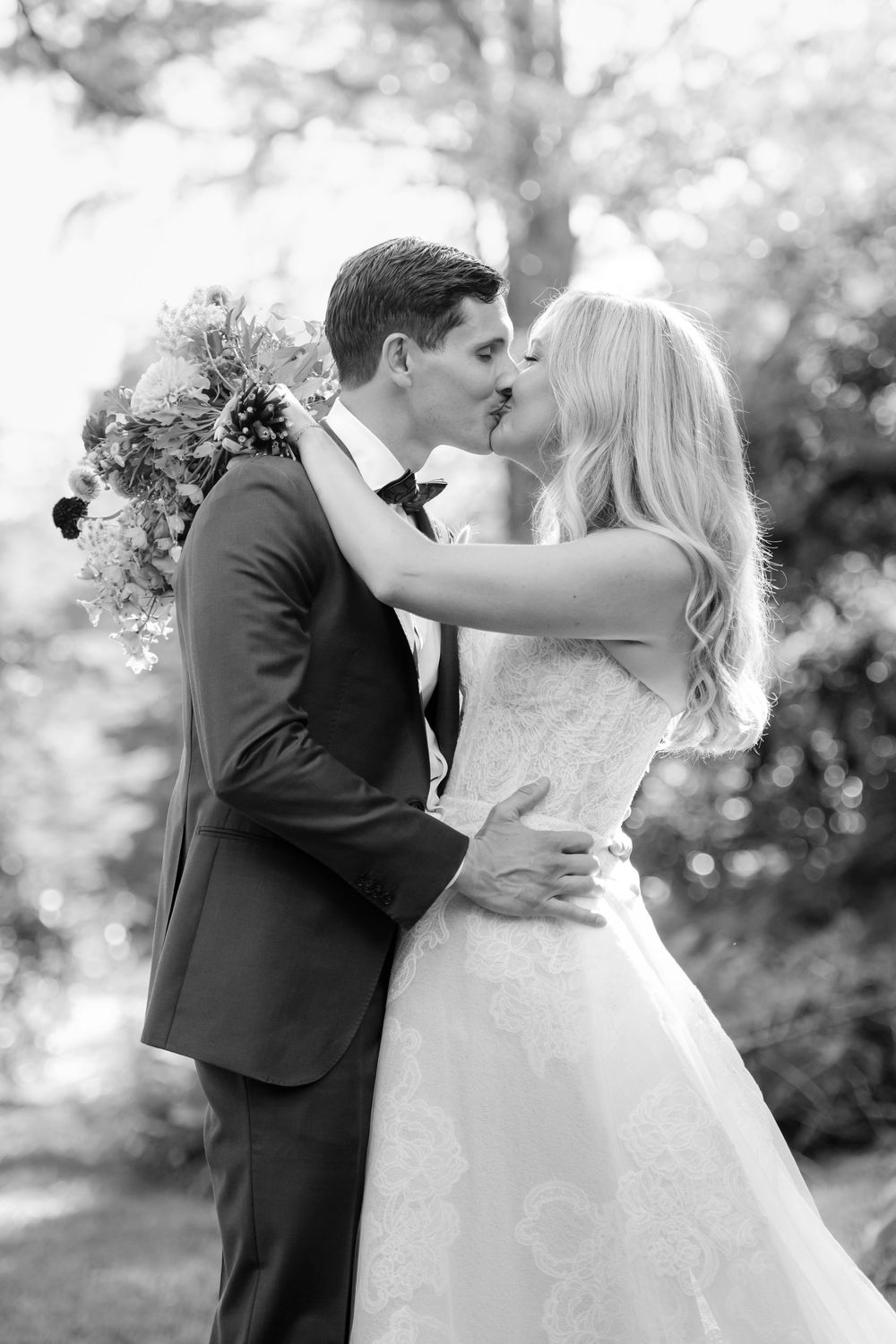 A romantic black and white wedding photo sequence showing a couple embracing and sharing a tender kiss outdoors.