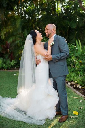 A romantic wedding couple dances and embraces in a lush garden setting with flowing white dress and grey suit.