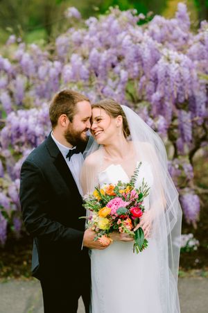 A romantic wedding photo series with cascading purple wisteria flowers creating a dreamy backdrop for the couple.