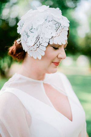 Delicate white lace bridal cap with intricate details adorns a romantic outdoor wedding look.