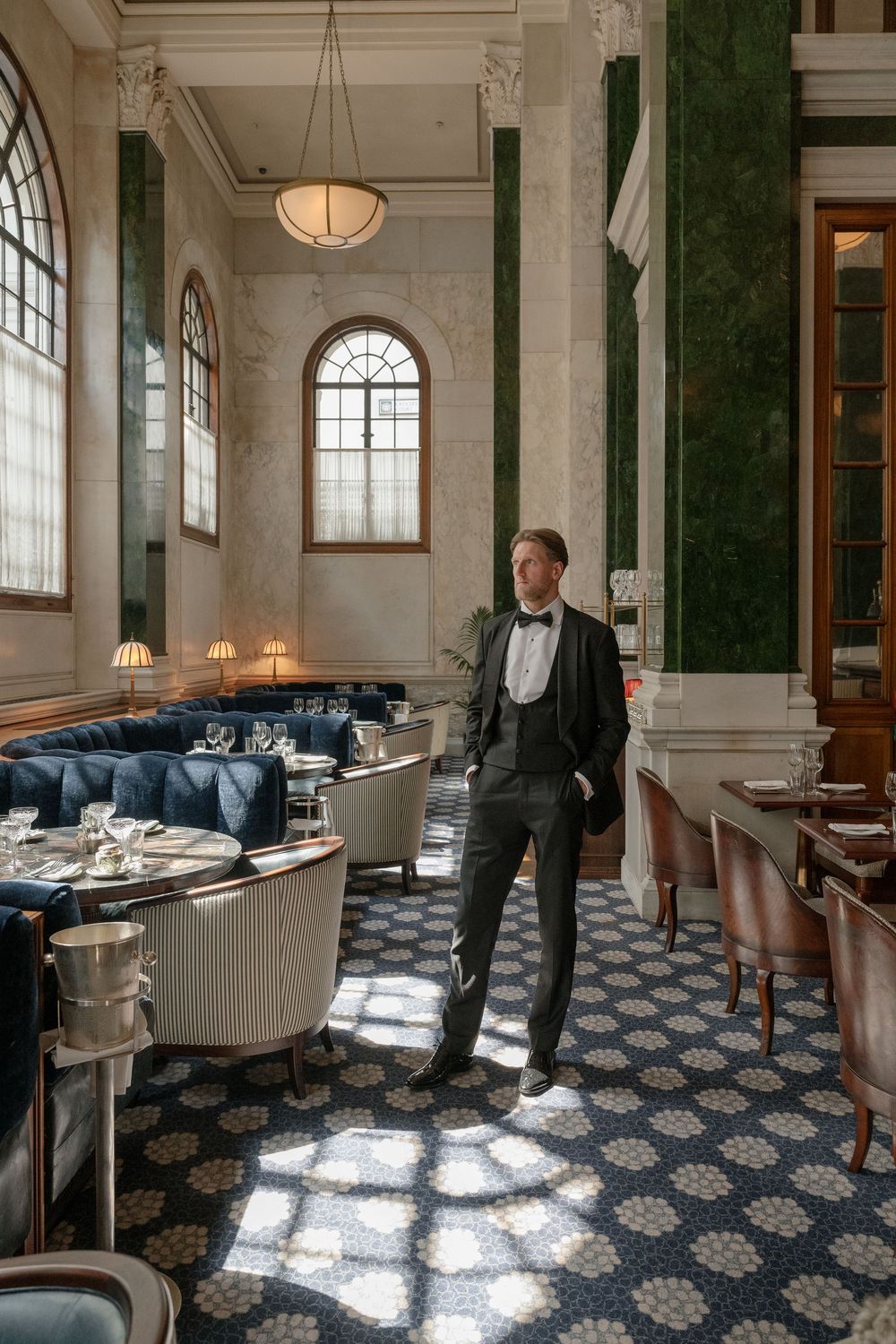 Luxurious restaurant interior with checkered floor, marble columns and elegant seating arrangements.