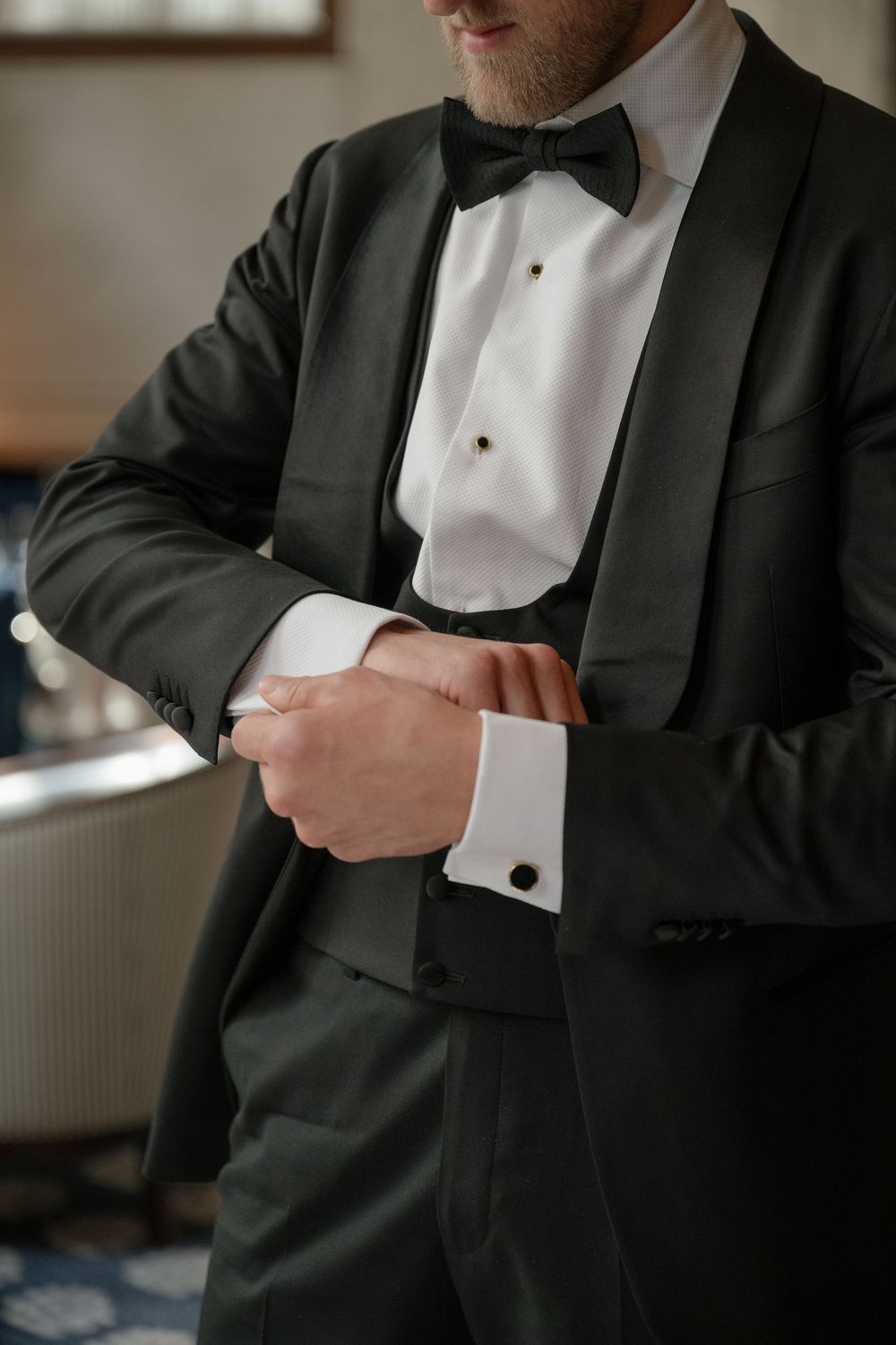 Close-up shots of a groom adjusting formal black tuxedo and white dress shirt cuffs during wedding preparation.