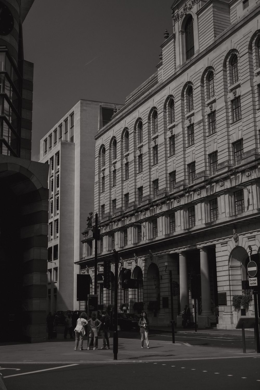 Black and white urban street scene with historic ornate building facade featuring arched windows and columns in London.