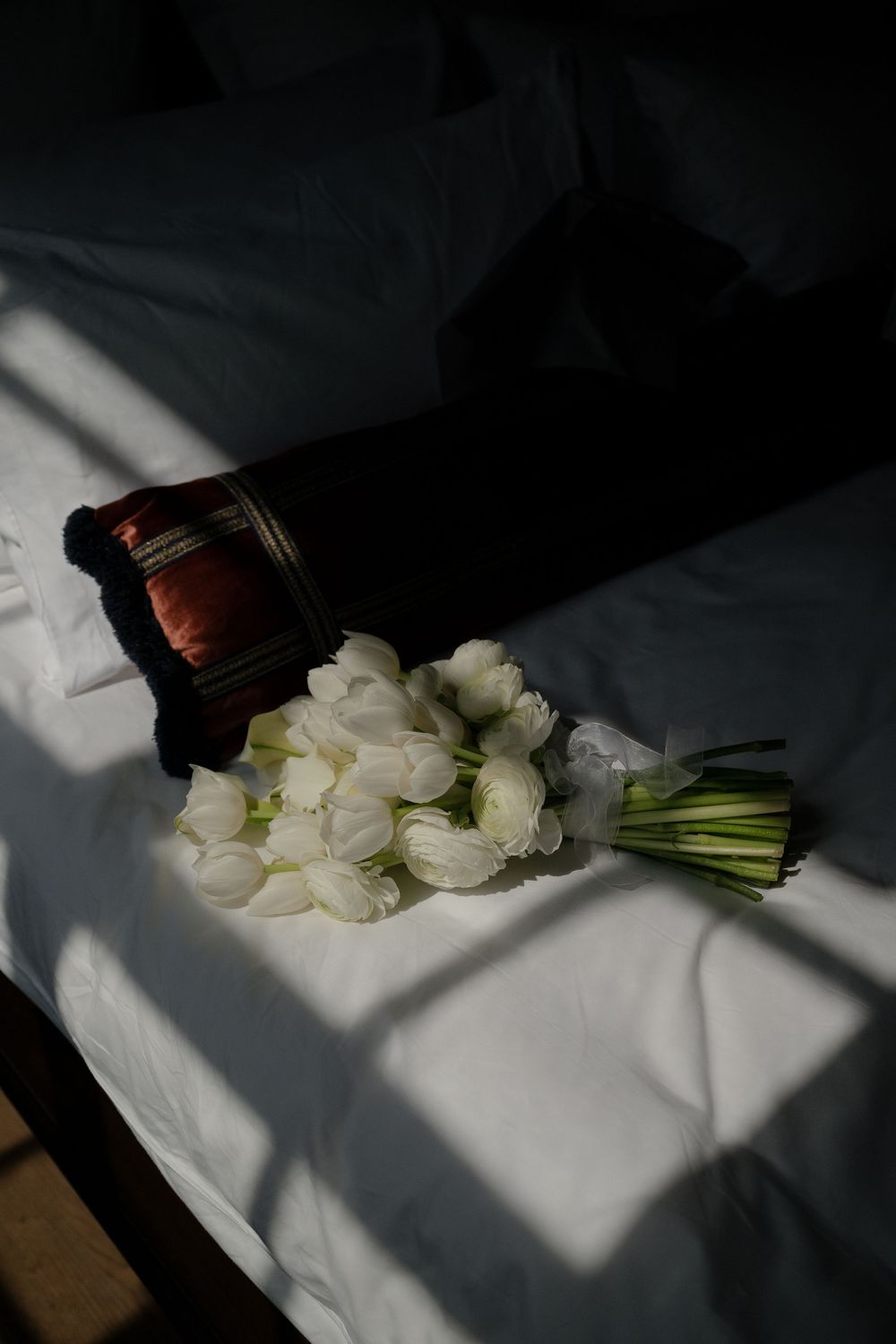 White roses laying in dramatic lighting on a white surface.
