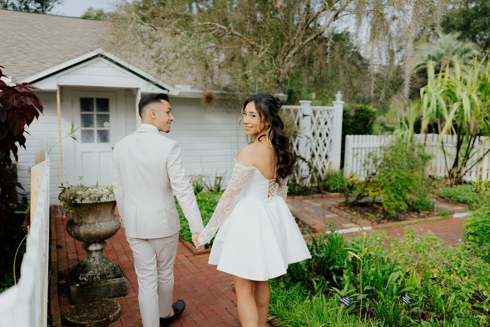 A romantic wedding photoshoot in a lush garden setting with white architectural elements.