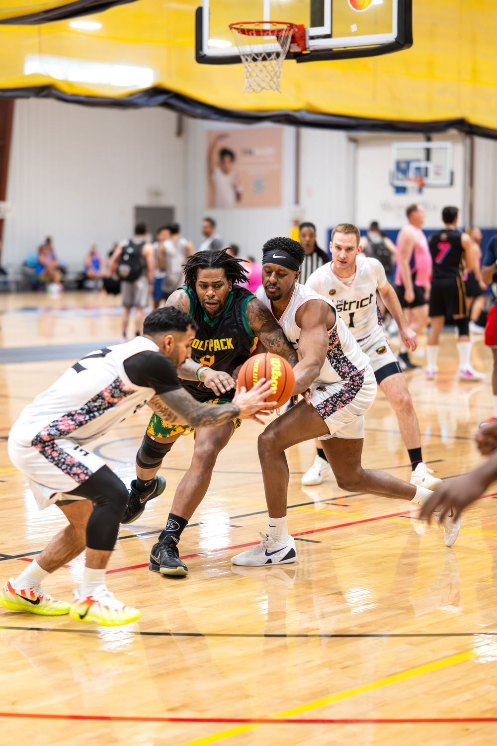 An athlete in the basketball tournament attempts to break through defenders on both sides of him at Sin City Classic hosted by the NGBA
