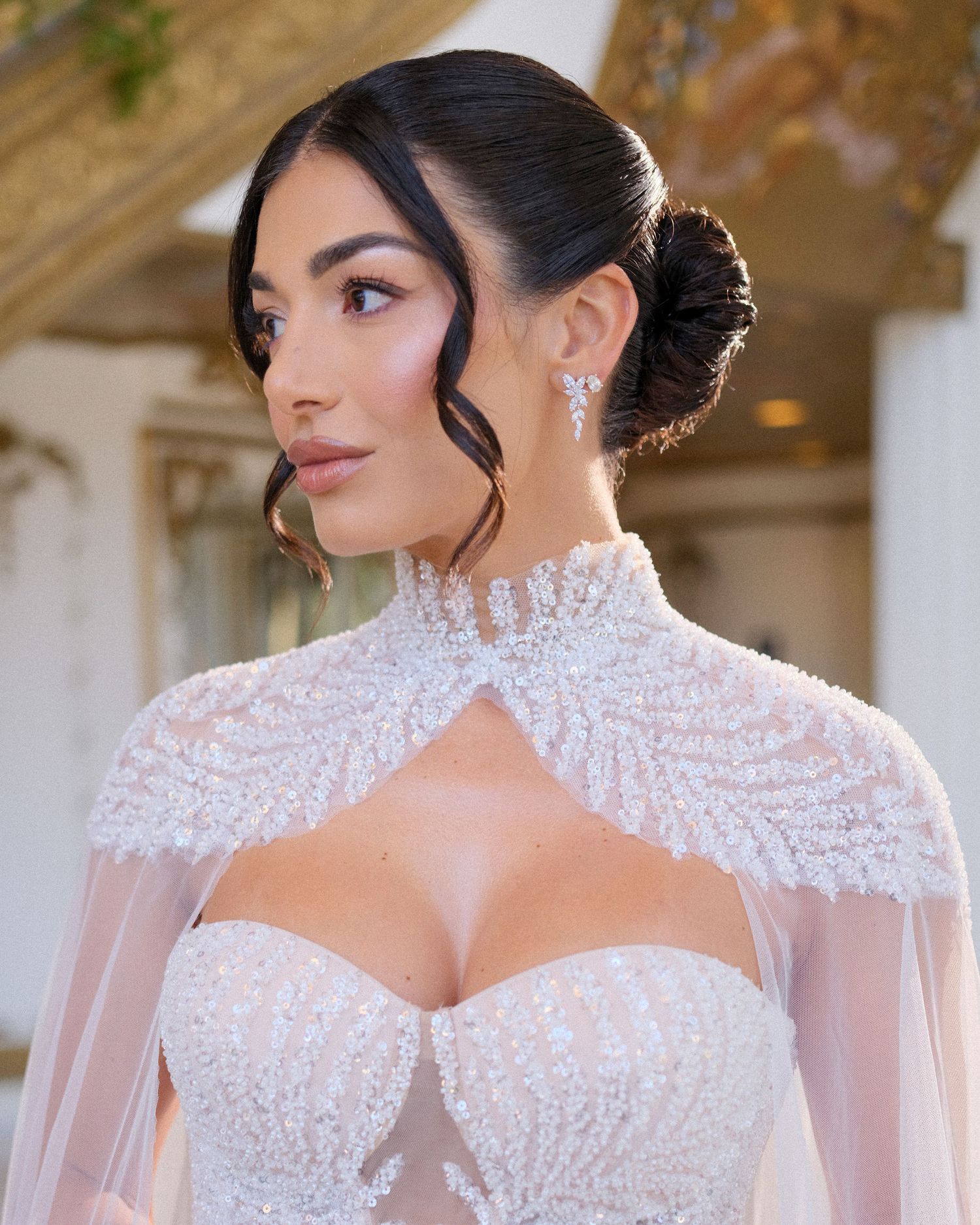 Elegant bridal look featuring a high-neck white lace gown with sheer details and sparkling crystal earrings.
