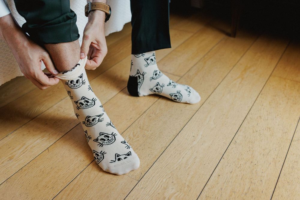 groom putting on cat pattern socks during wedding preparations