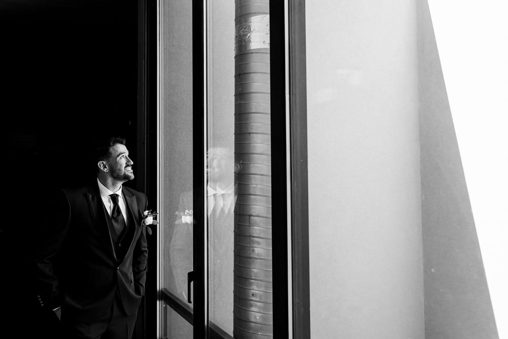 black and white photo of the groom standing by window light during wedding preparations at DOMA Portugal