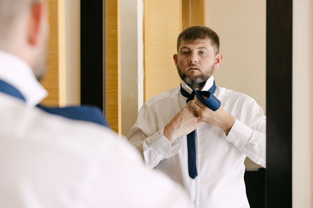 Groom adjusting tie in Albufeira hotel room