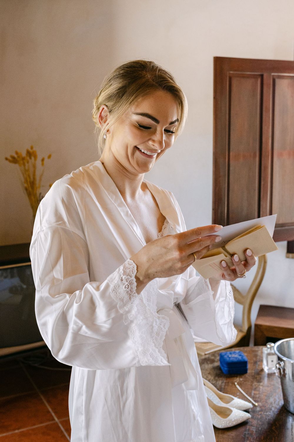 A person in a white robe smiles while getting ready in a bright interior room with wooden details  at Monte do Serrinho