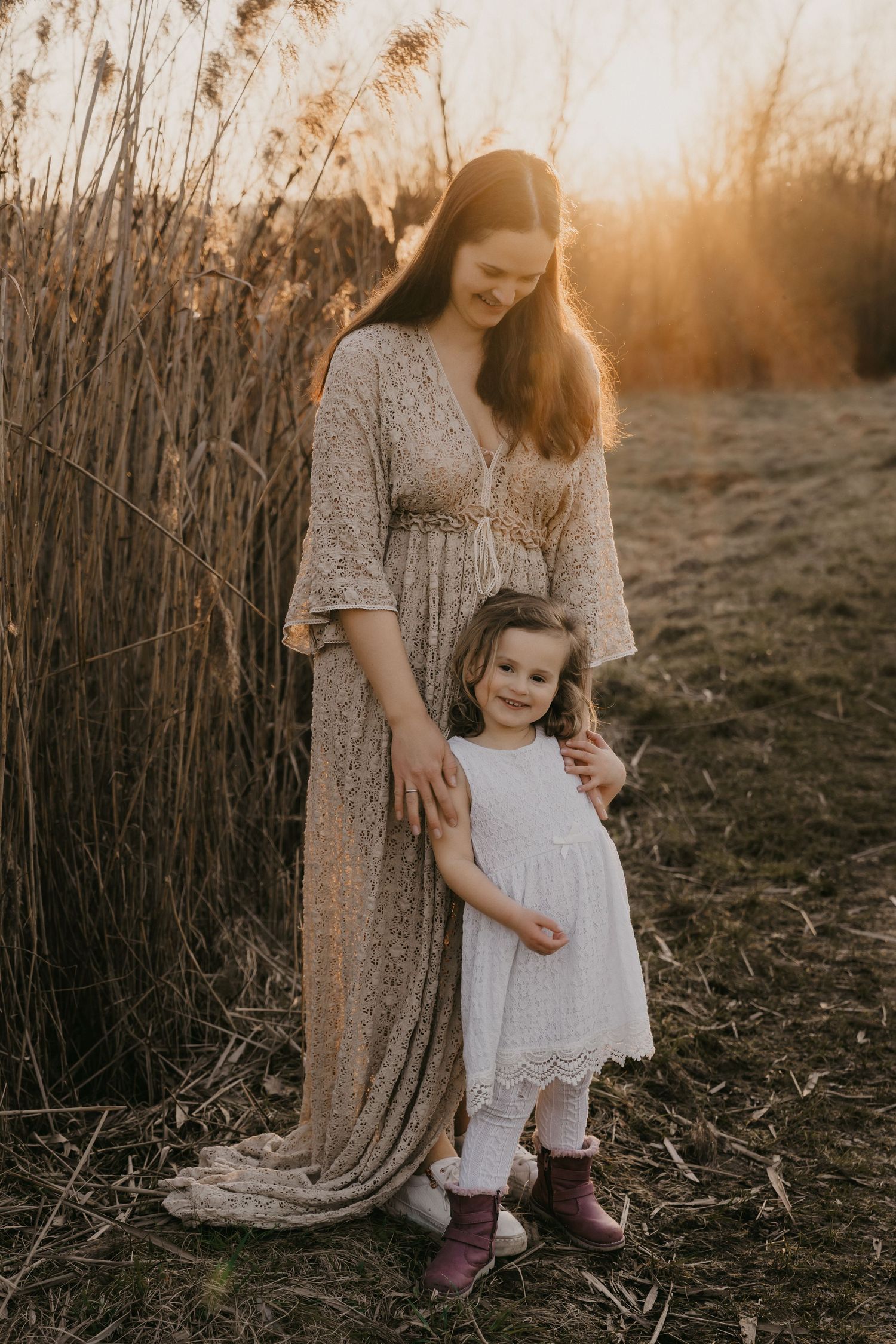 A heartwarming sunset photo session in a rustic field shows tender moments between parent and child in matching outfits.