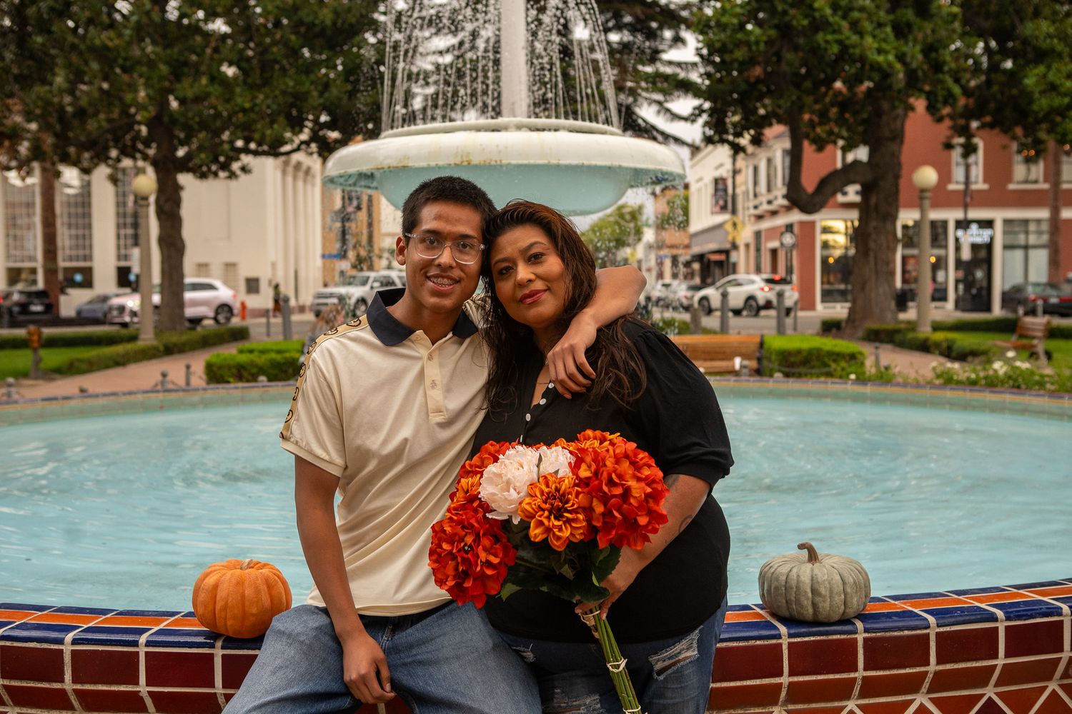 A couple celebrates a special moment together near a swimming pool with bright orange flowers.