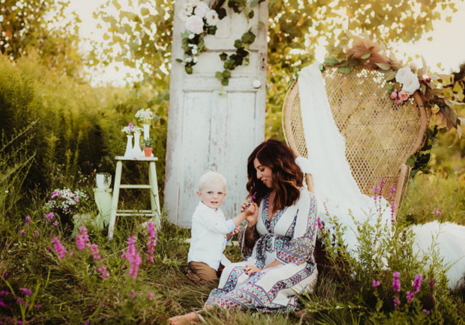 A vintage-style outdoor photo session in a garden with white furniture and pink foxglove flowers at golden hour.