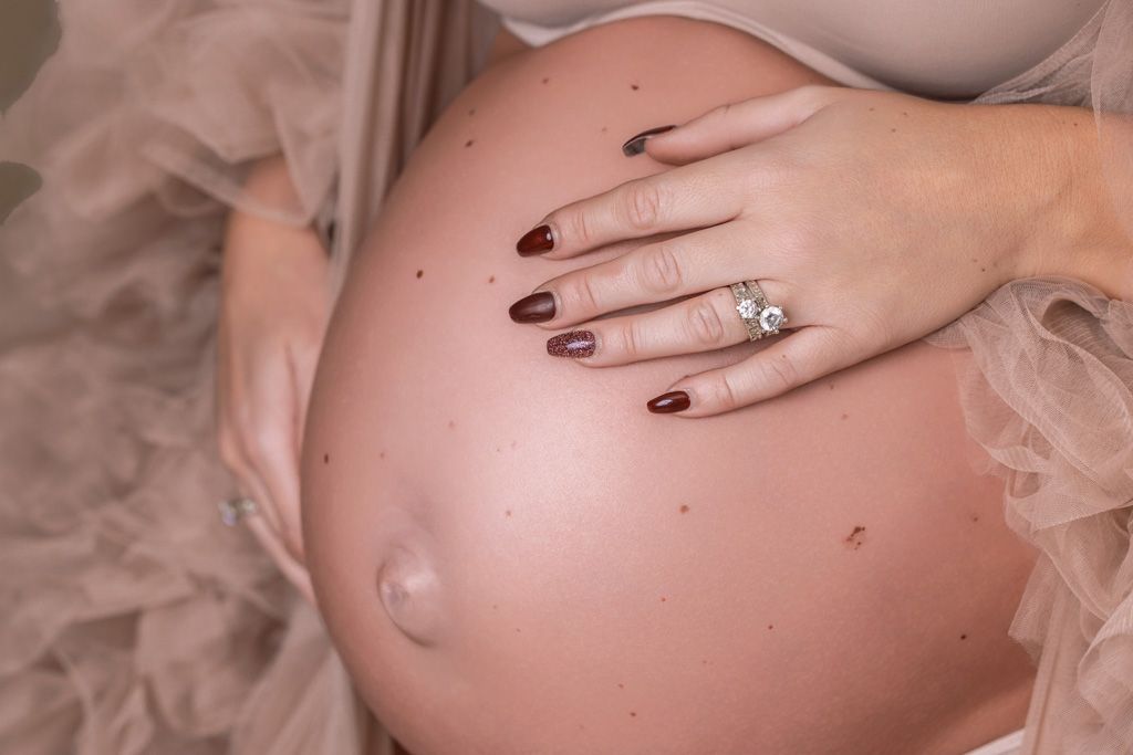 A pregnant woman's bare belly is shown in a series of artistic maternity photos with hands gently touching the bump.
