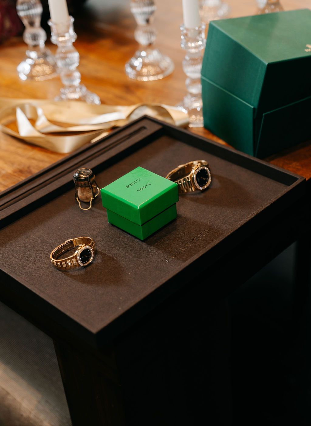 A series of jewelry displays showing gold rings on dark trays with green jewelry boxes in a retail setting.