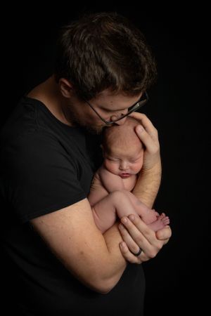 Newborn baby with parent high contract black backdrop