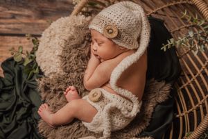 tiny newborn wearing sleepy hat rustic details