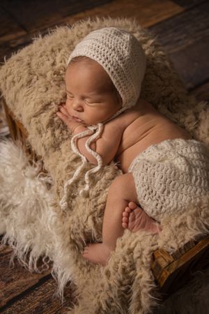 sleeping newborn boy in bed prop and neutral styling in Mississauga Studio