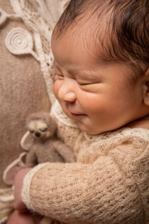 newborn session sleeping baby smiling and holding sloth