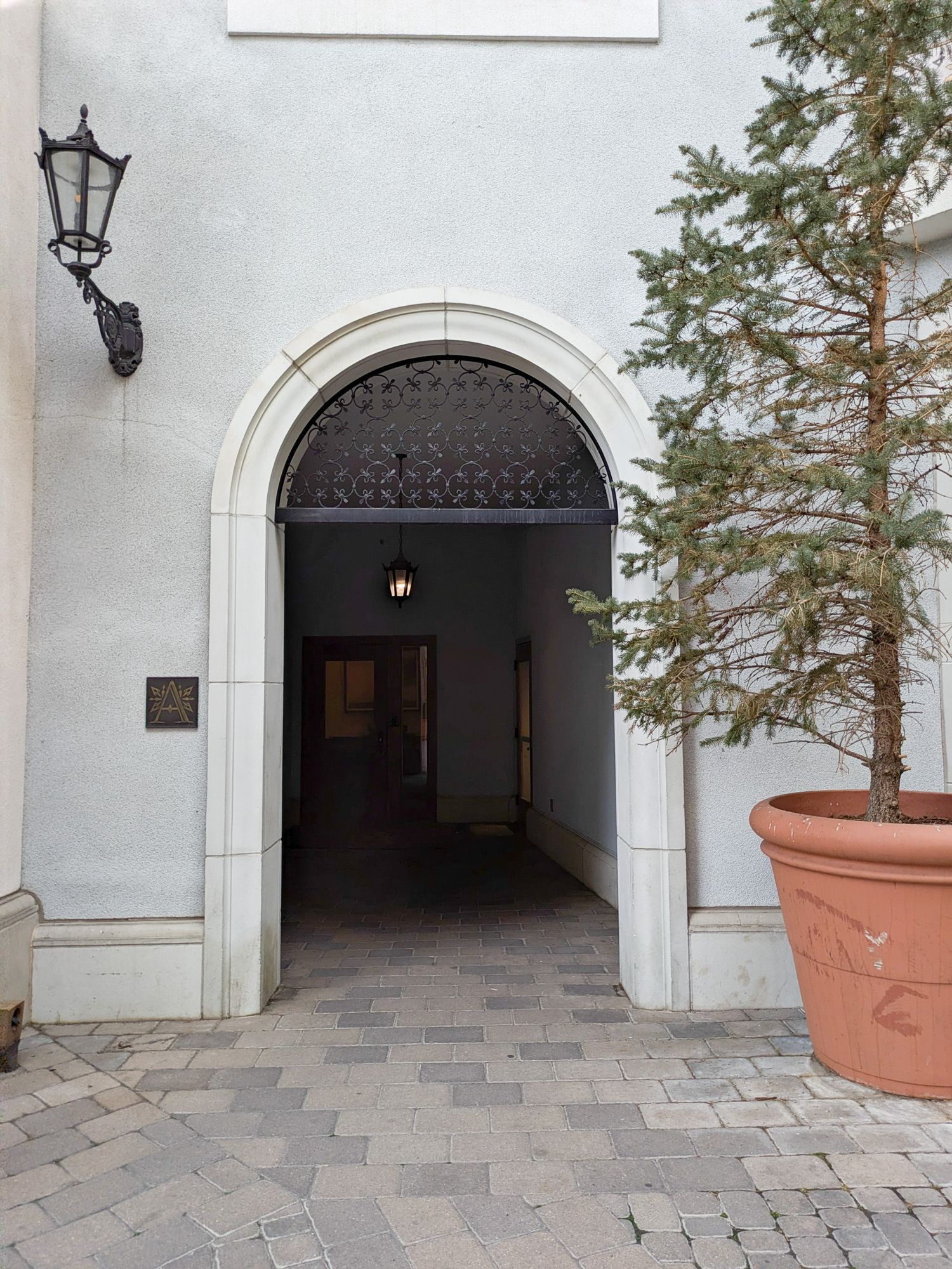 A series of white stone archways with decorative black metal gates and lanterns along a paved courtyard walkway.