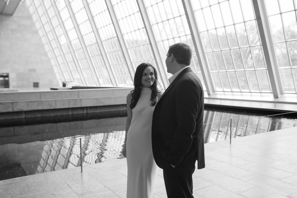 Couple sharing a romantic moment in a bright modern building with large windows.
