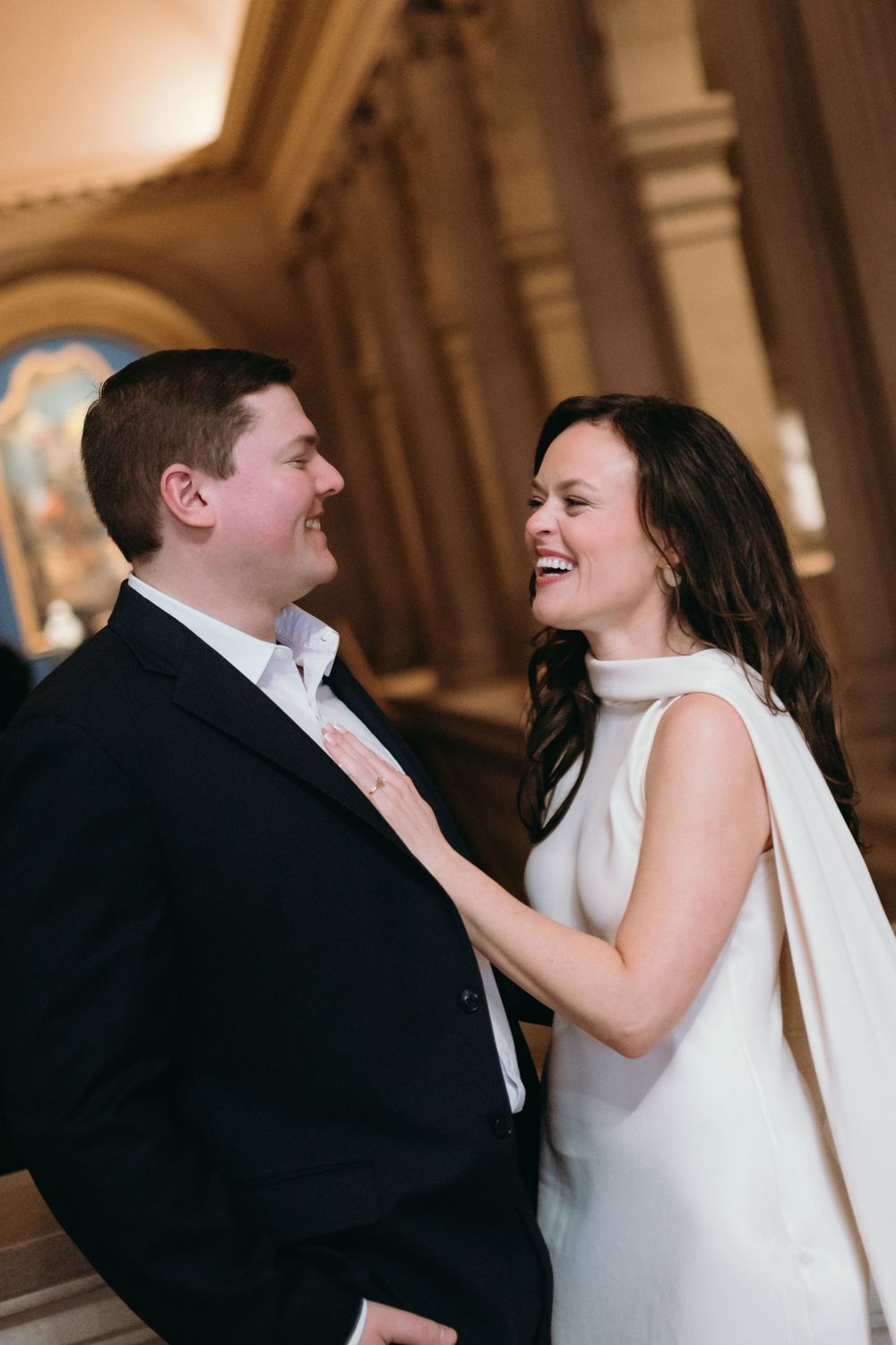 A candid moment of laughter shared in an ornate hallway with classical architecture.