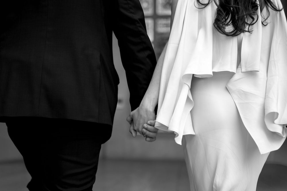 Elegant couple in formal attire walking through museum hallways.
