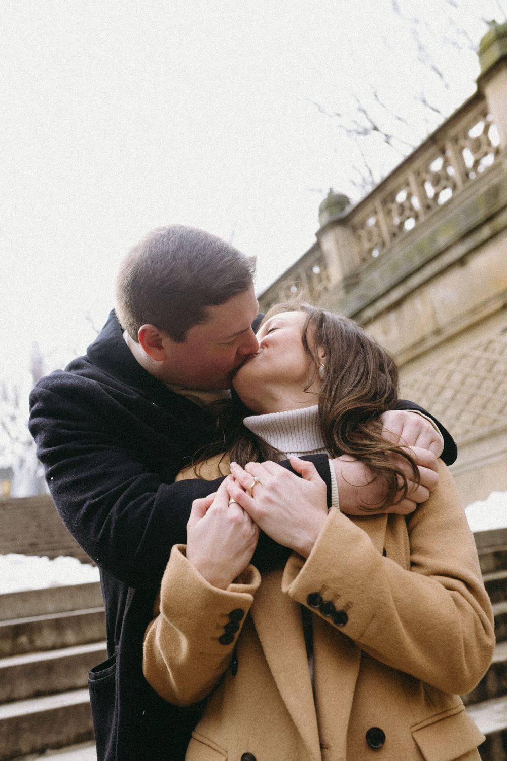Romantic couple sharing tender kisses in a series of candid outdoor moments while wearing winter coats.
