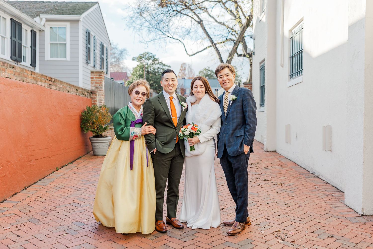 Wedding party members gather on a brick pathway outside historic buildings in Charleston, South Carolina.
