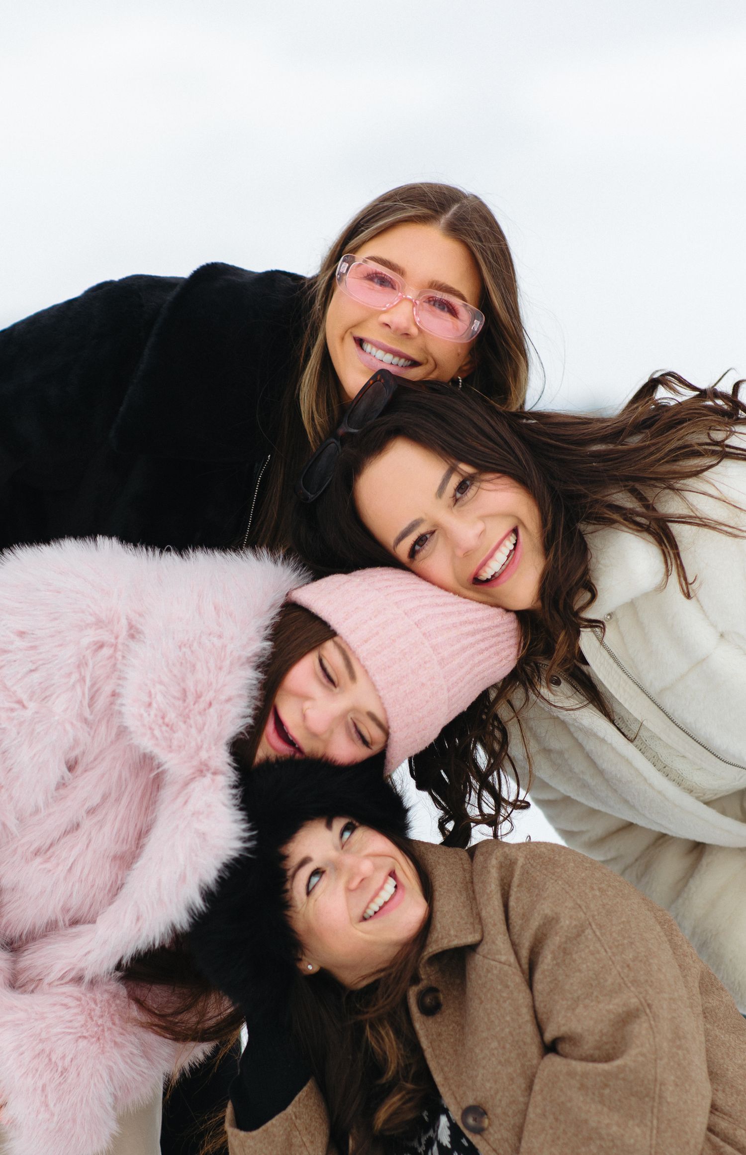 Friends lying in snow laughing and wearing winter coats.