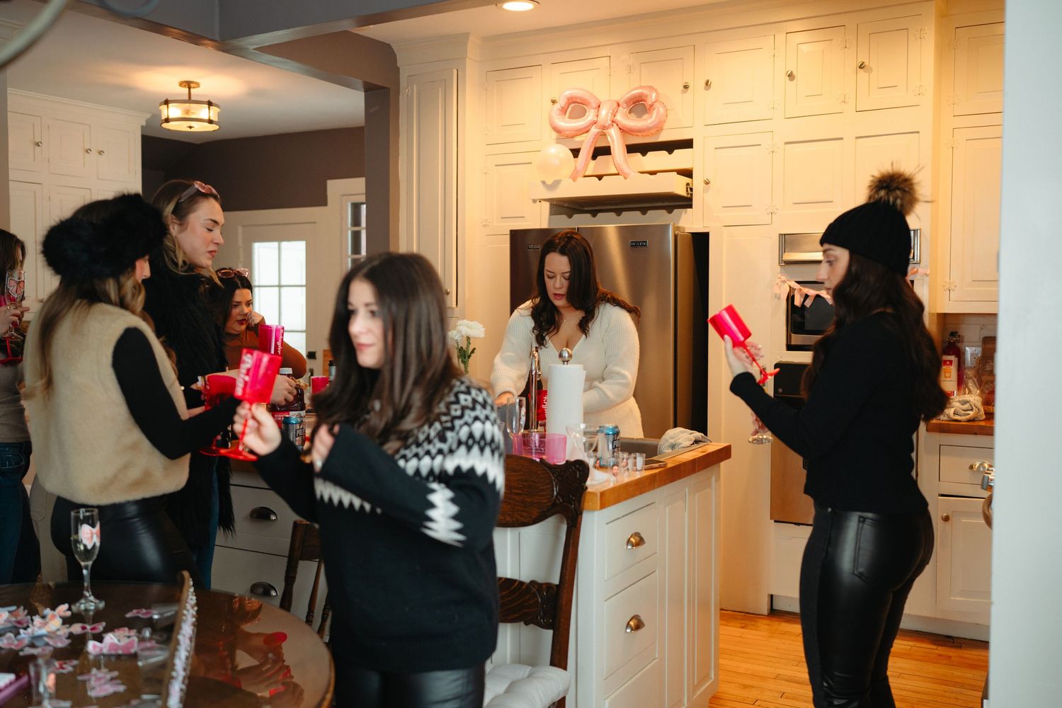 Group celebrating at a party with drinks in a modern kitchen setting.