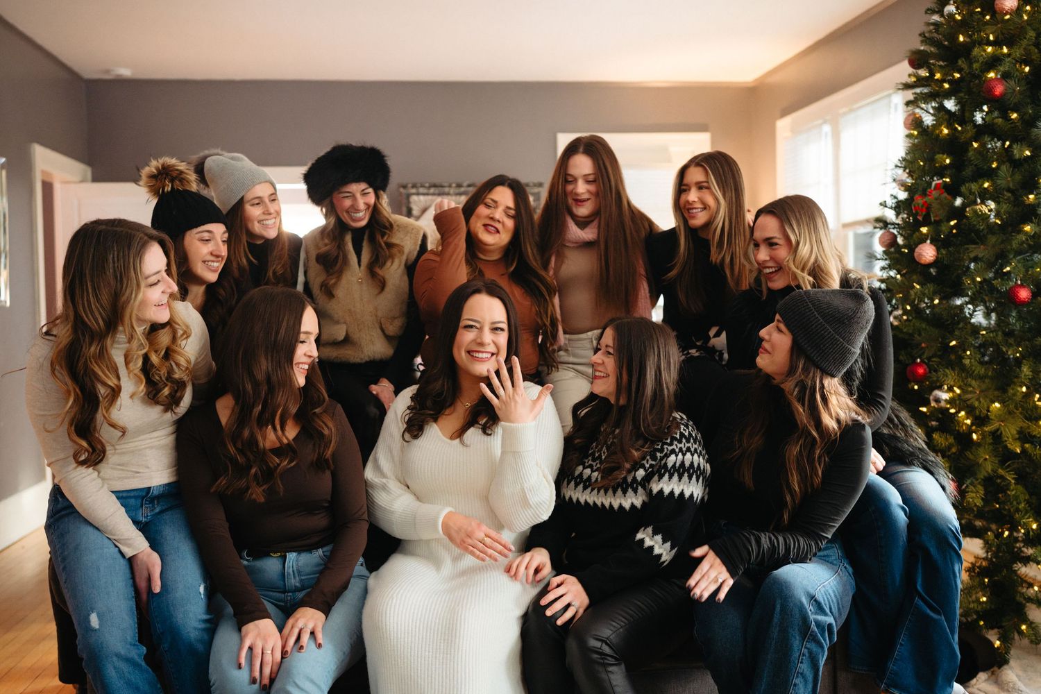 A group of friends laughing and celebrating together in a cozy room decorated with Christmas trees.