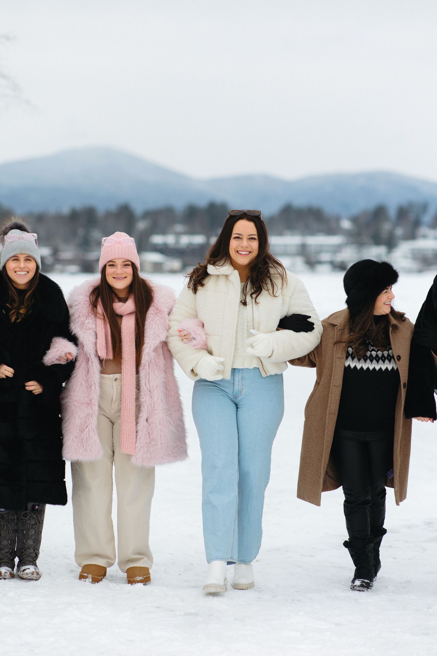 Group walking together in winter coats against a snowy mountain backdrop.
