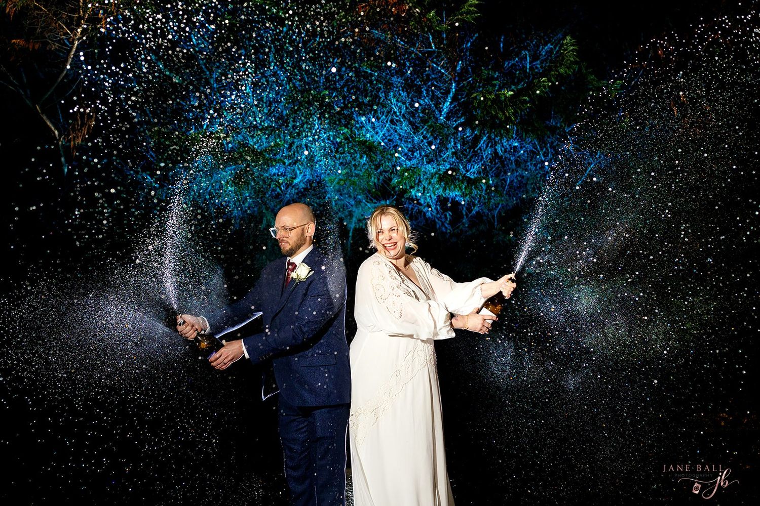 Two performers on stage with sparklers creating light trails against a dark starry background.
