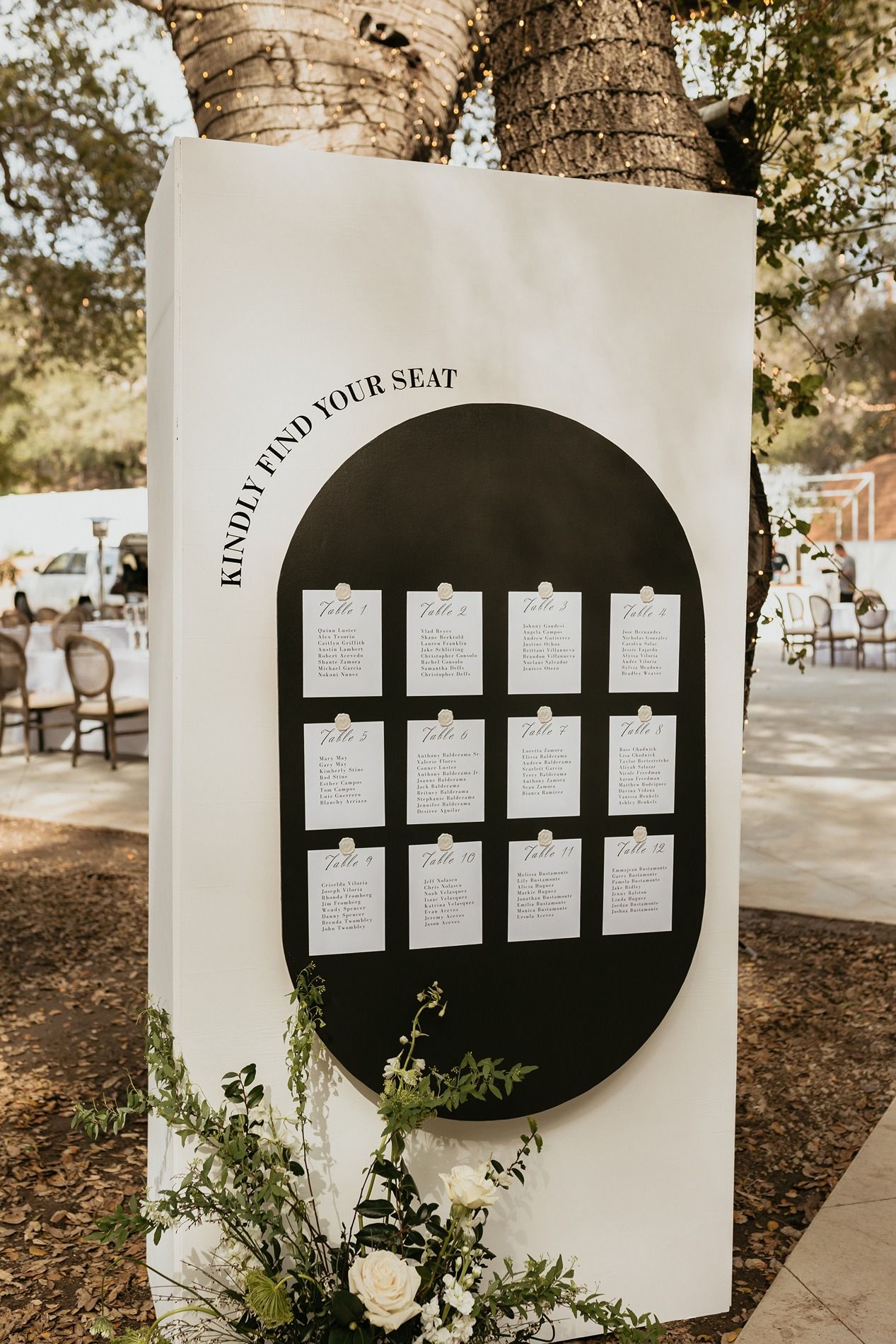 Black and white circular wedding seating chart displays mounted on white walls with delicate floral accents at The Oaks at Duncan Lane.
