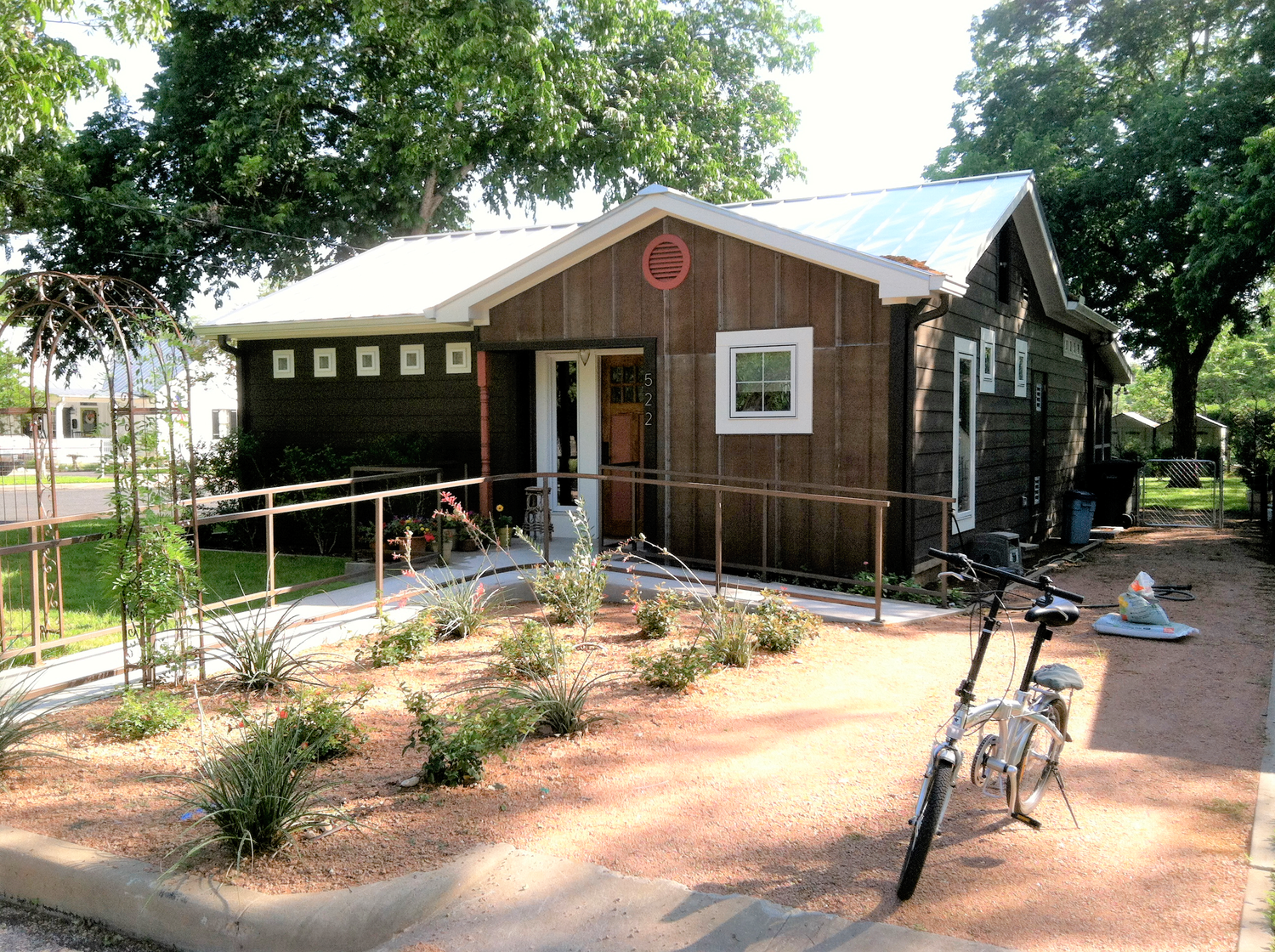 Panoramic view of multiple rustic brown wooden cabins nestled among trees with white trim and covered porches.