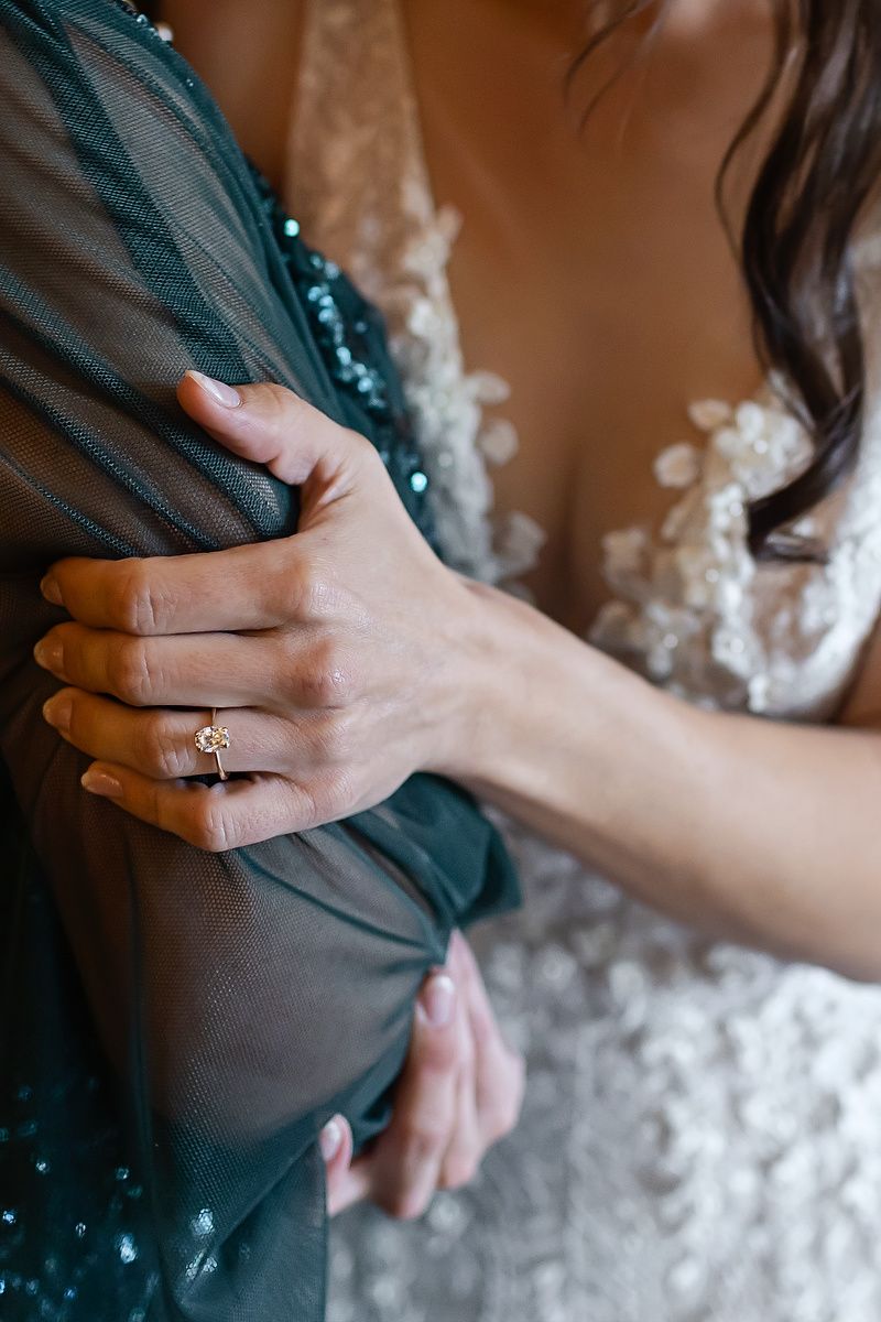 Close-up series of hands wearing wedding rings against dark fabric and white lace details.