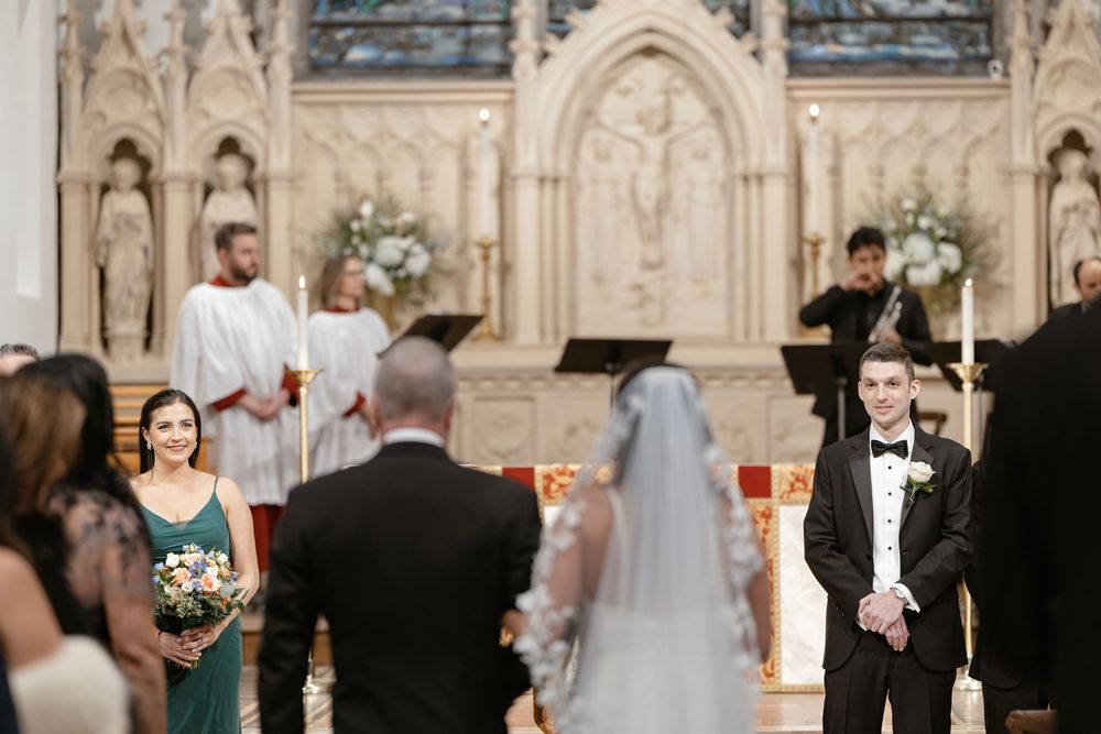 A wedding ceremony takes place in a grand cathedral with ornate Gothic architecture and stained glass windows.