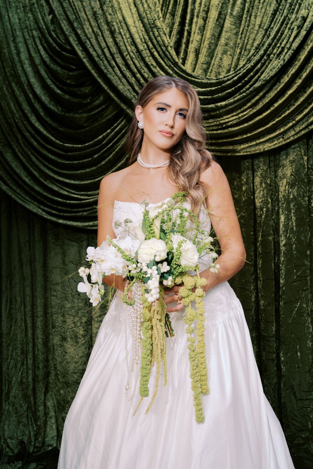 Elegant bridal portrait series against dark green velvet backdrop with white floral bouquet and cascading greenery.