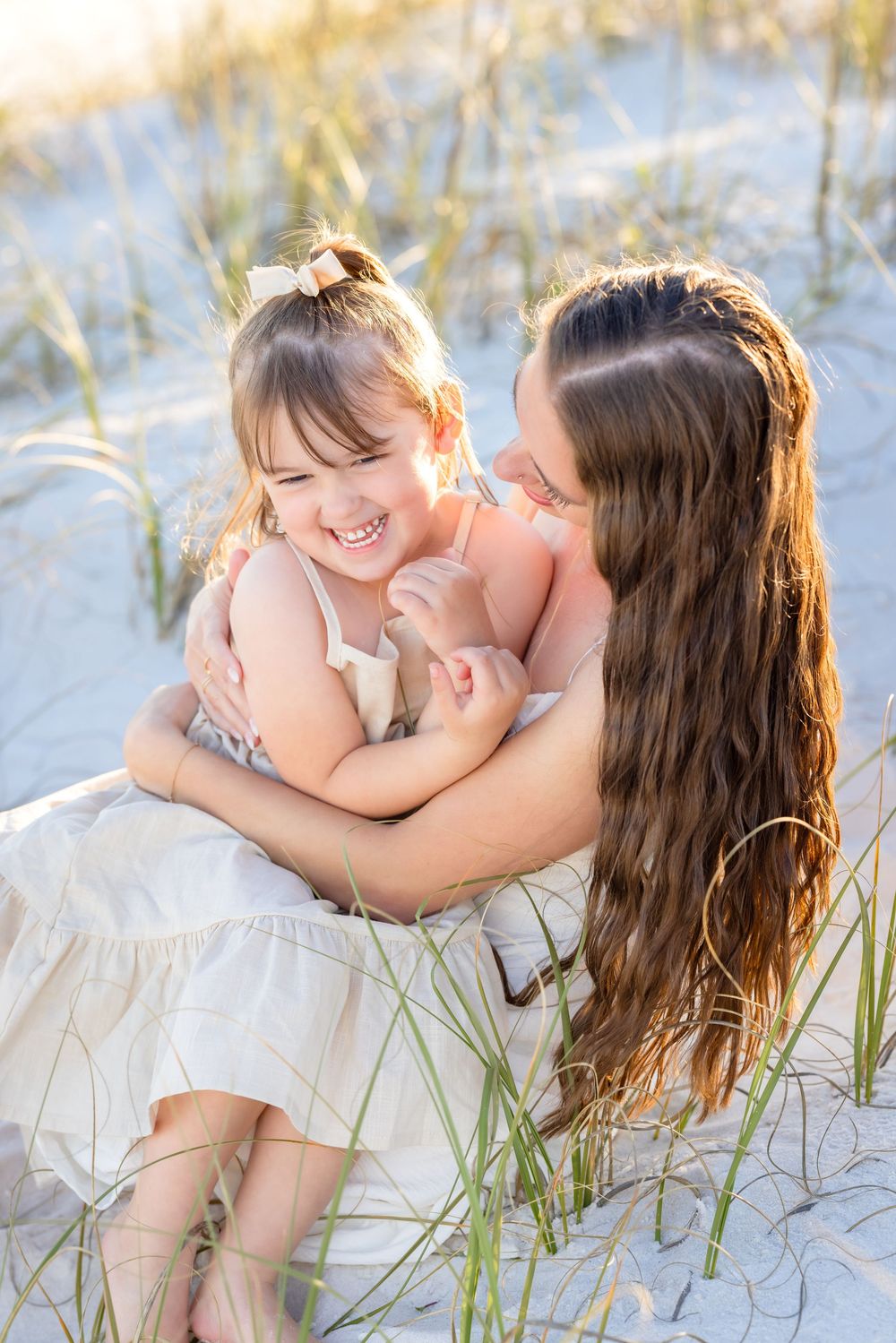 A sweet moment captured in a series of photos showing playful interaction on white sand dunes with beach grass.