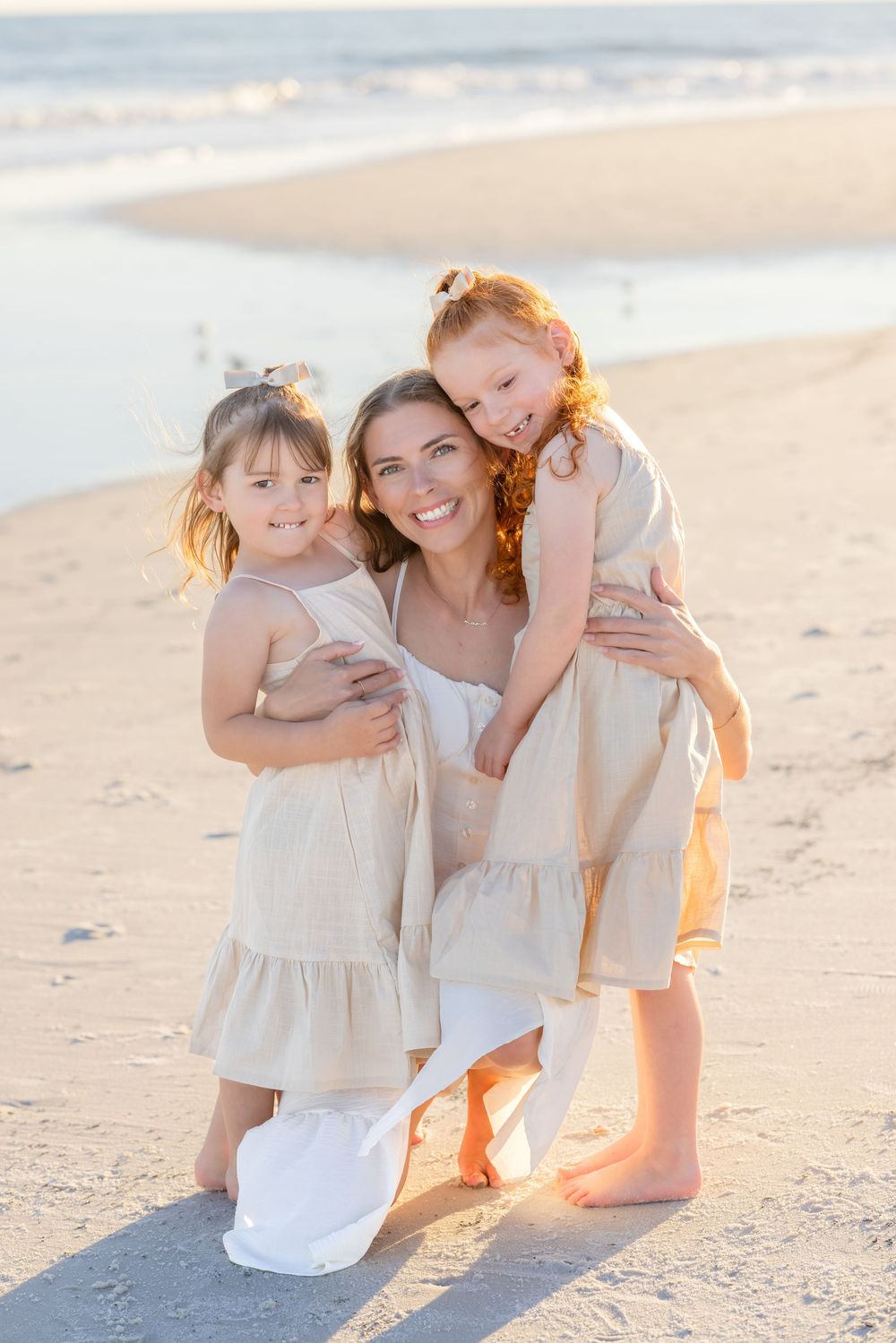 A loving family moment captured at sunset on a sandy beach with warm golden light.