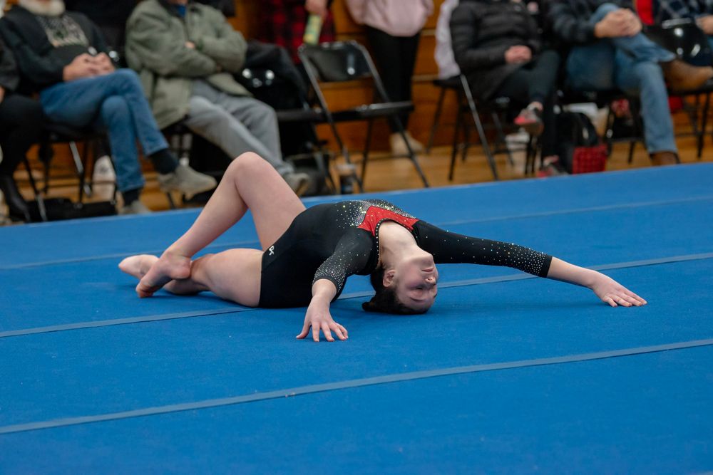 Gymnast performing a tumbling sequence on a blue competition floor mat.