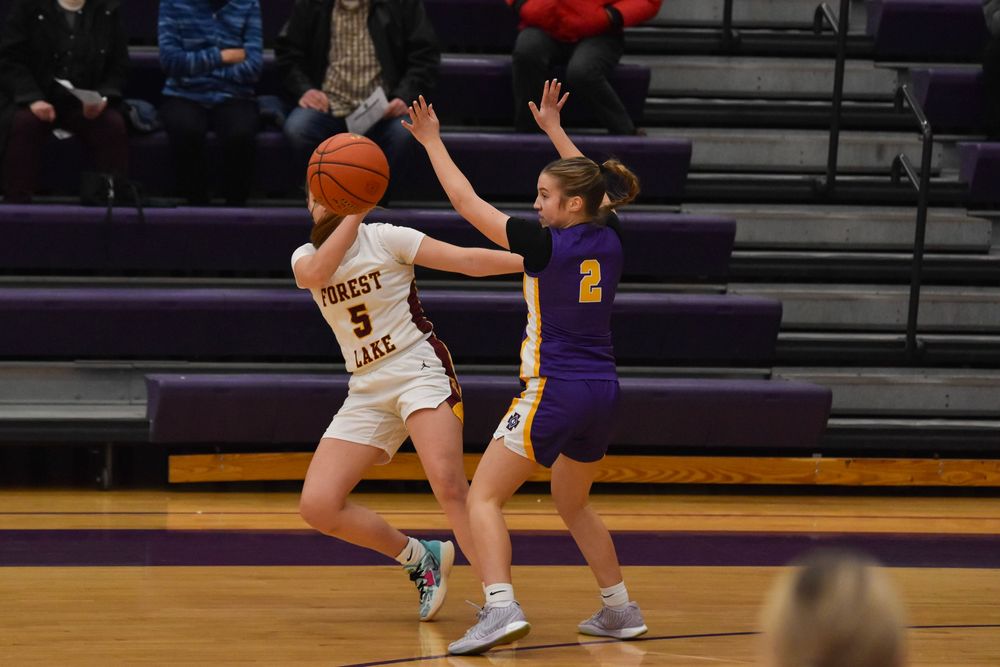 Basketball players battle for position during competitive game on indoor court.