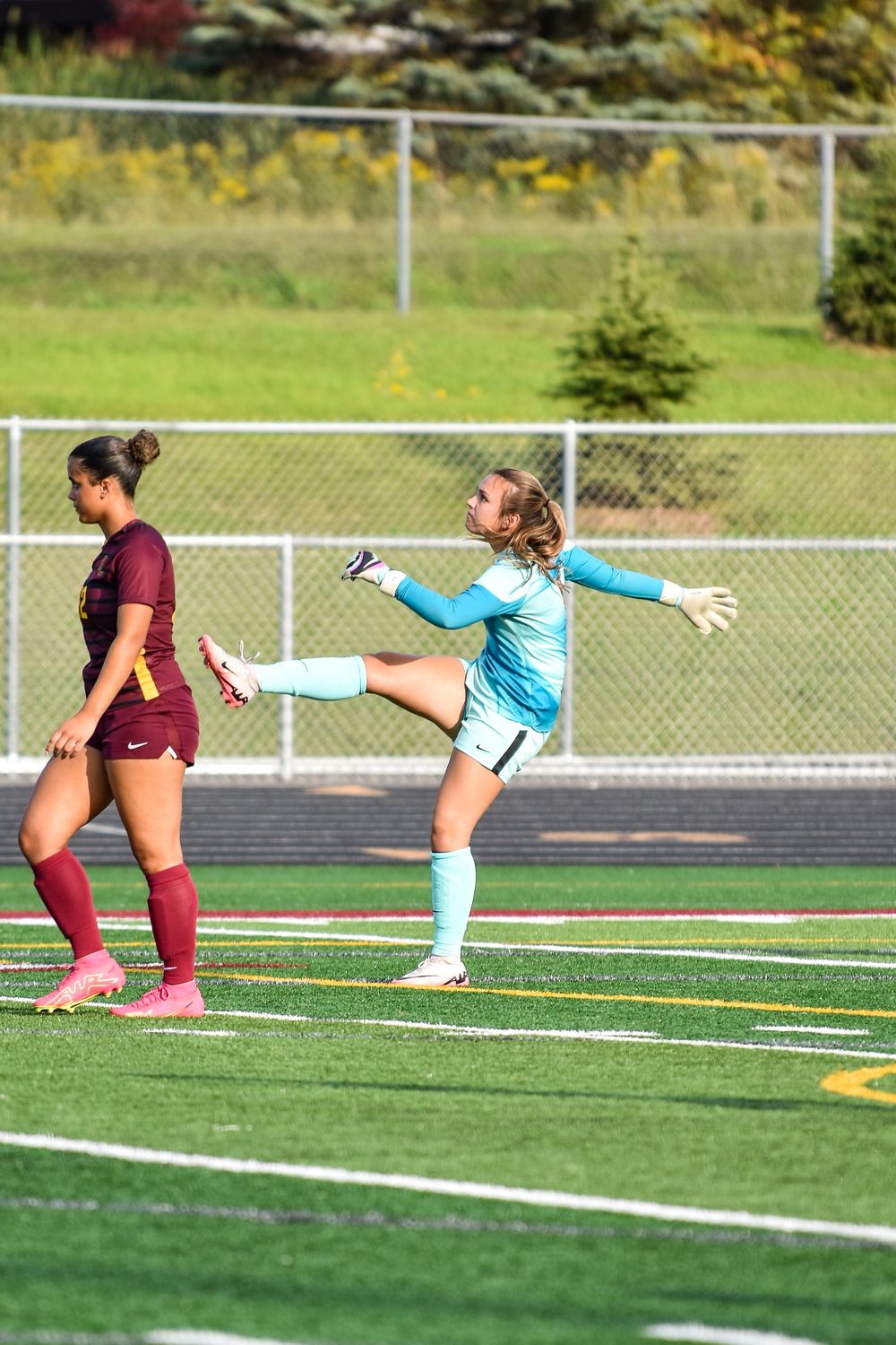 Soccer players compete for ball possession with dramatic sliding tackle.