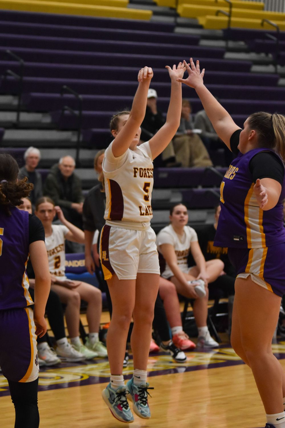 Basketball players jump and compete for ball during indoor game.