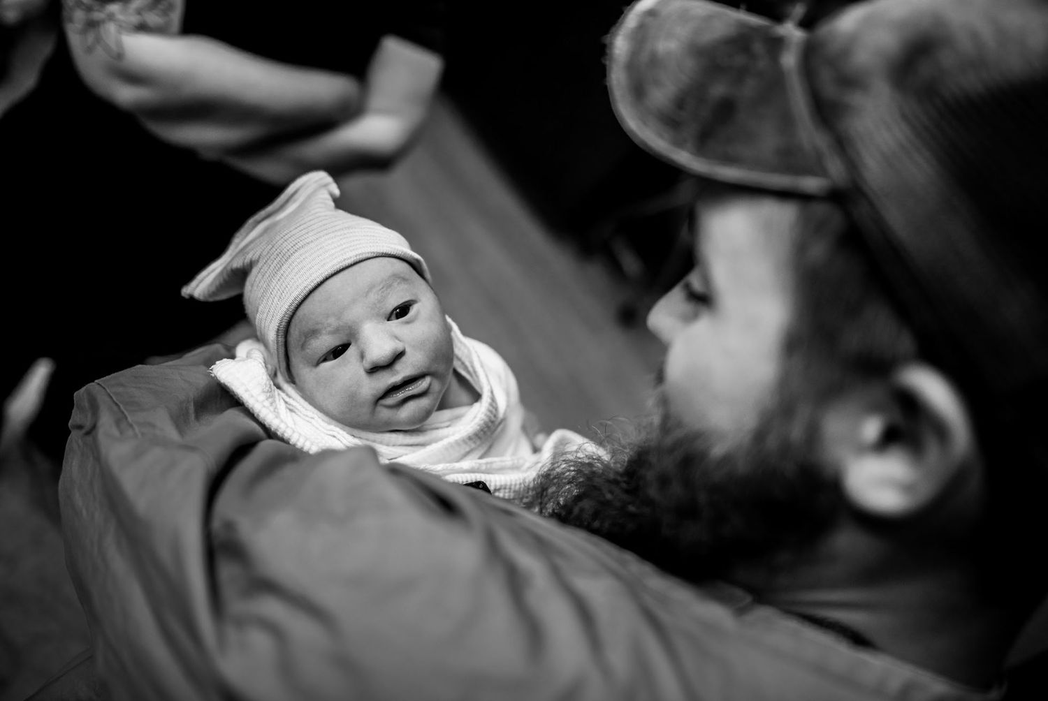 A black and white portrait of a swaddled newborn baby.