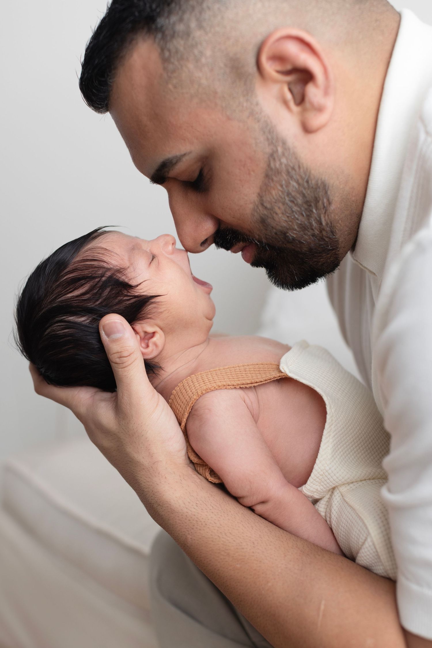 A mother tenderly touches noses with her newborn baby, cradling the infant gently in her arms.Elizabeth Lang Surrey