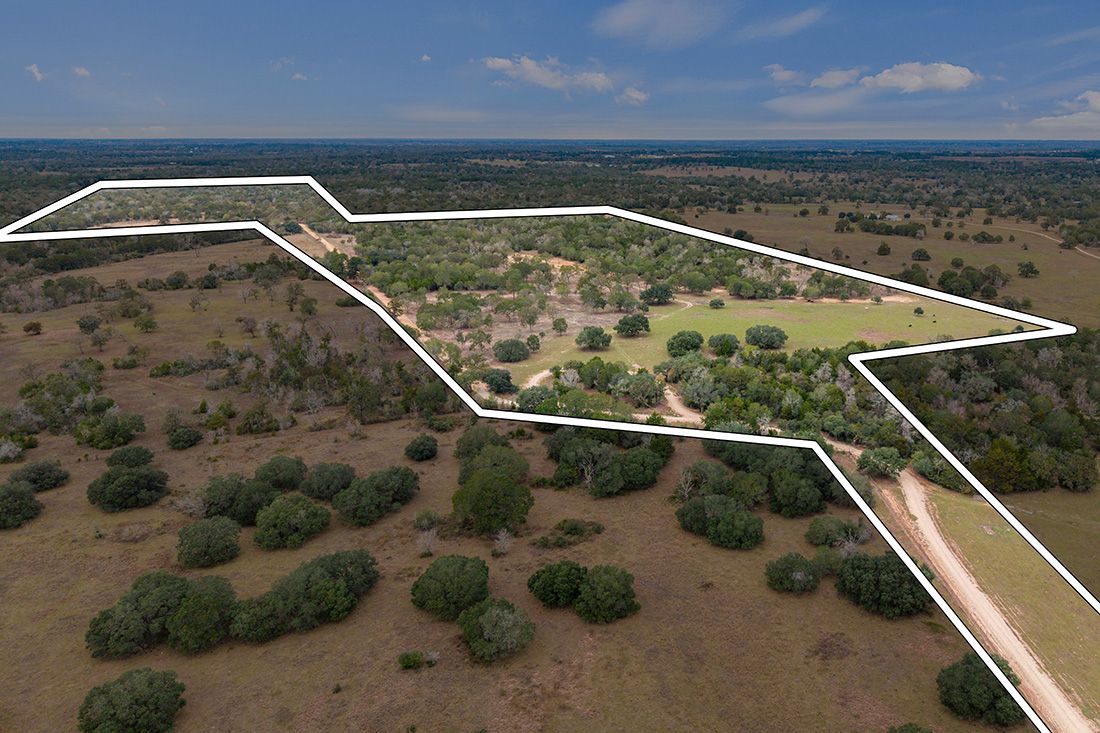 Aerial view of a rural Texas property with scattered oak trees, open pastures, and a homestead, outlined by white boundary lines.