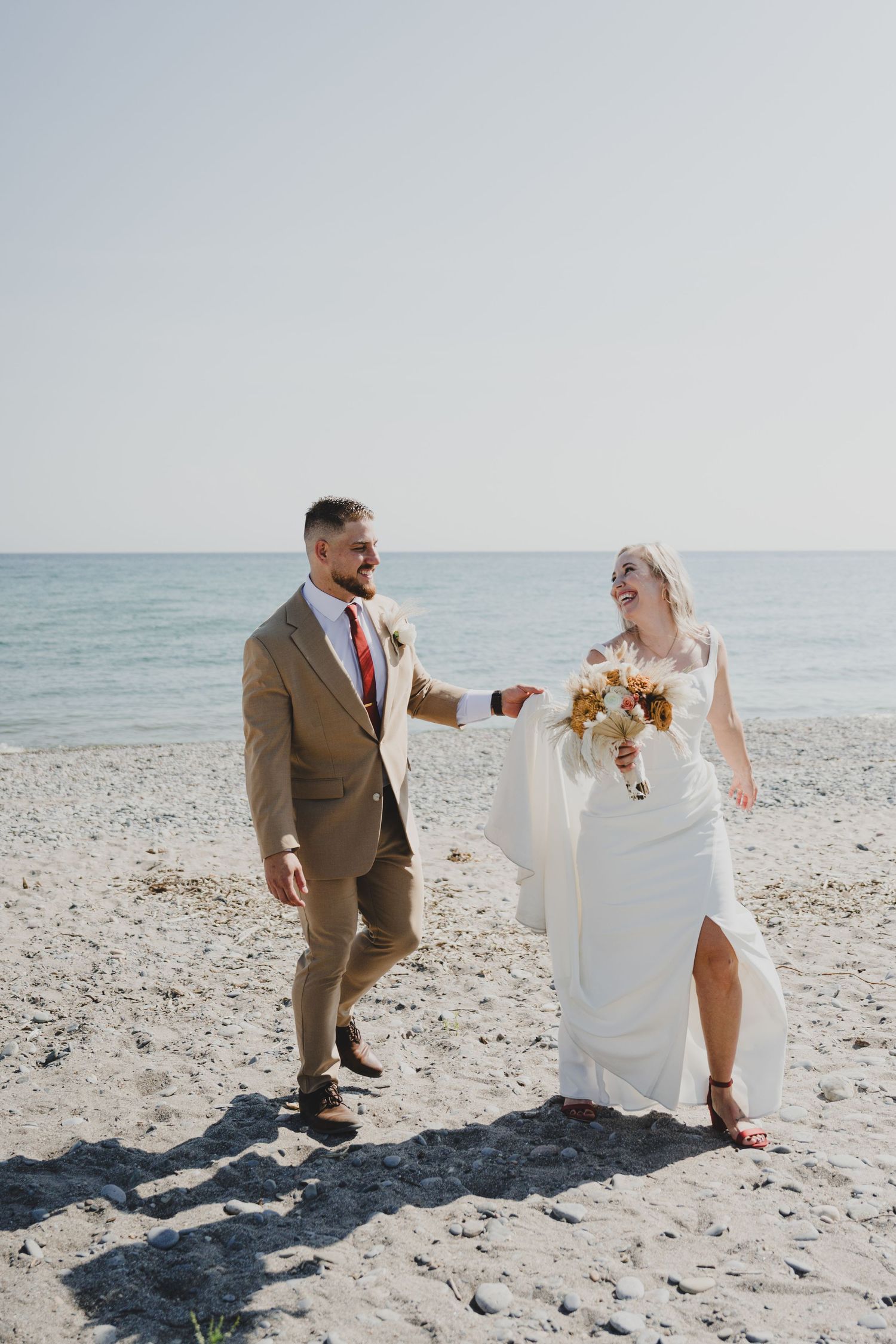 Newlyweds walk together on a wooden boardwalk surrounded by lush green forest ferns and trees.